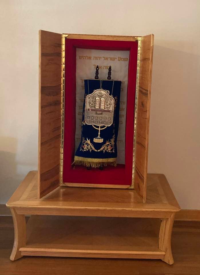 The wooden ark on a wooden stand, doors open and lined in red velvet, with the scroll standing inside in its dark blue covering and silver breastplate
